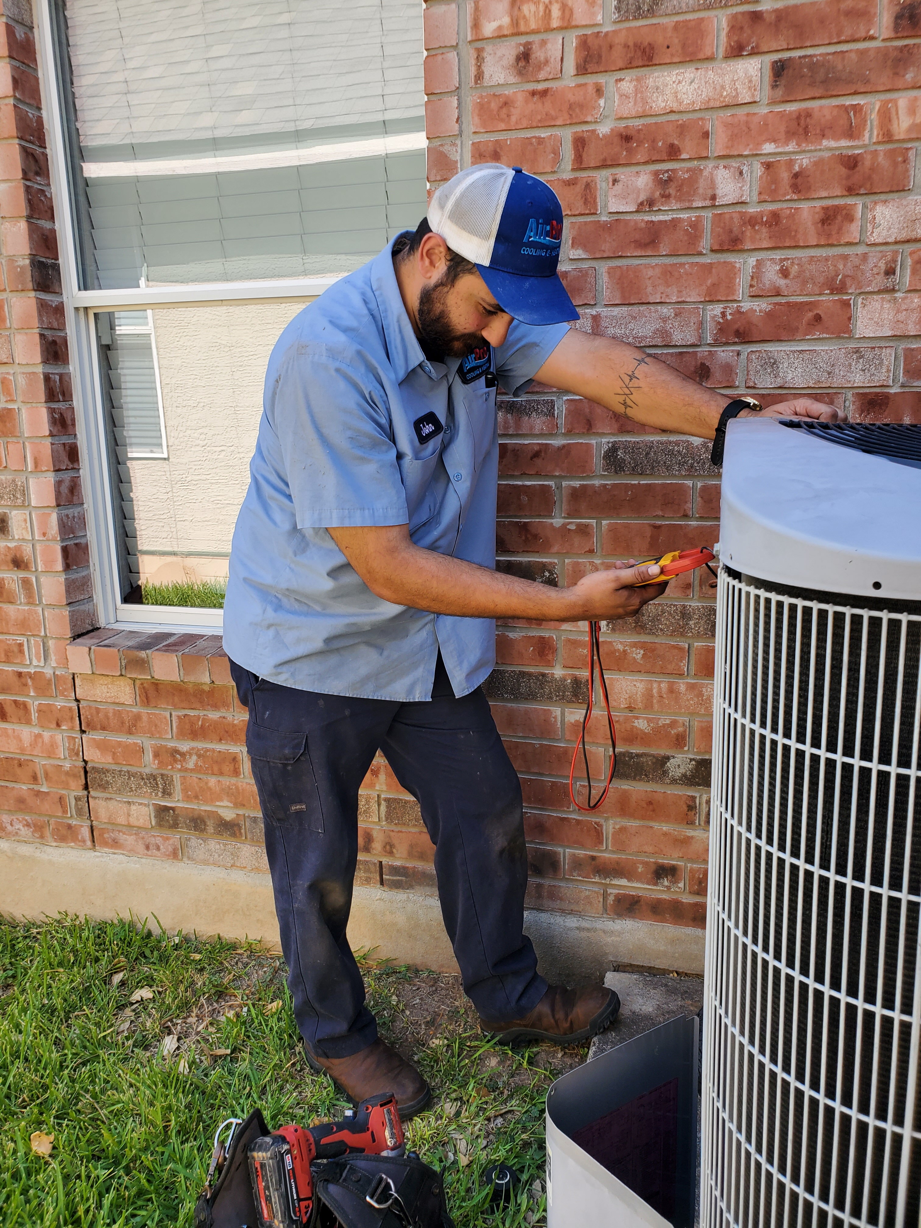 AirPro technician inspecting an outdoor AC condenser unit with a multimeter