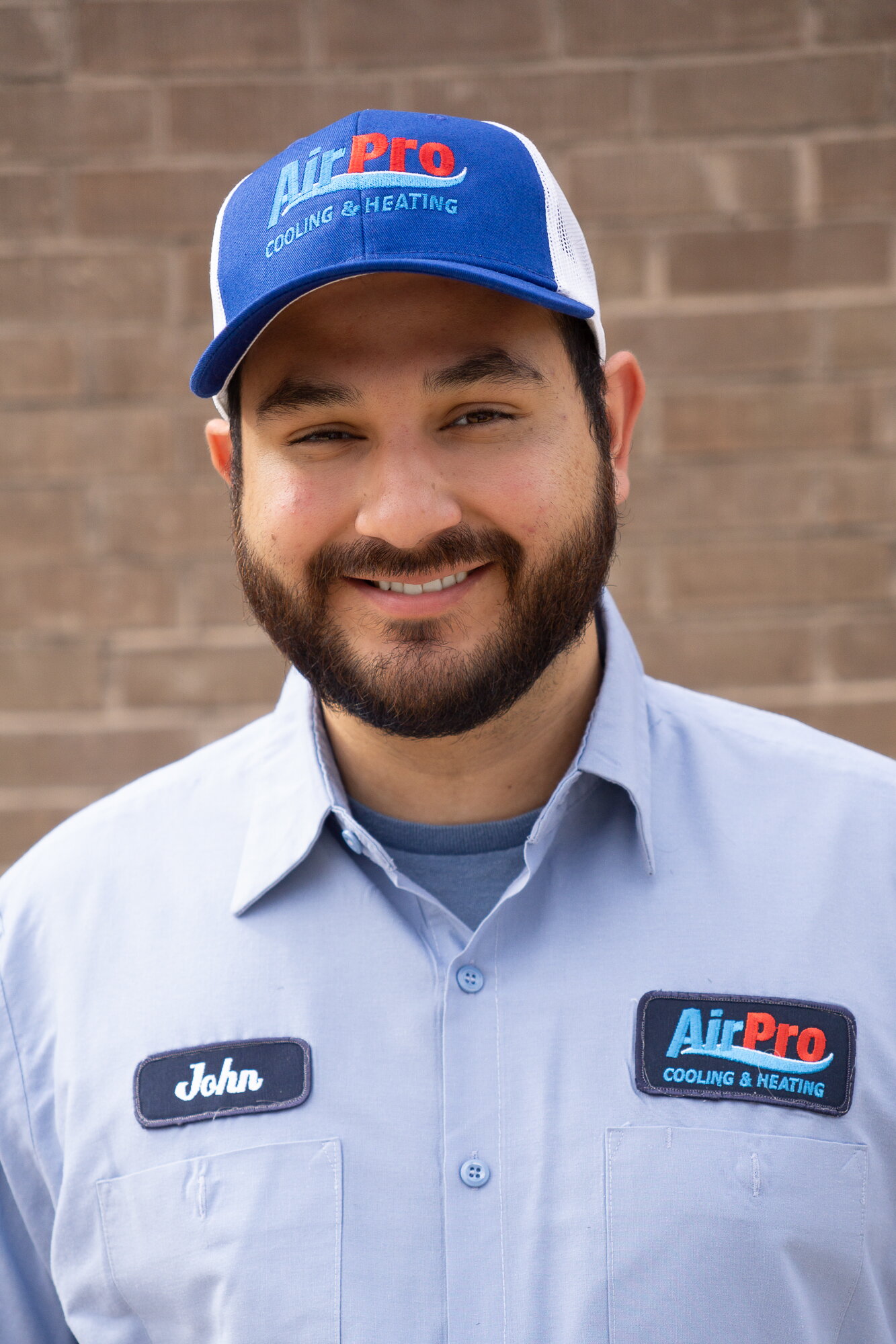 AirPro technician John, smiling in a branded cap and uniform