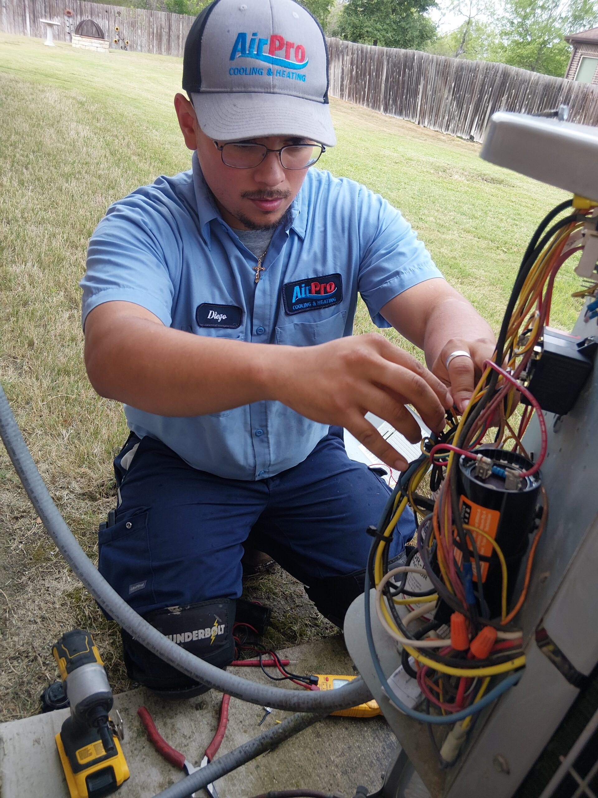 An AirPro technician in a branded uniform servicing an outdoor AC unit