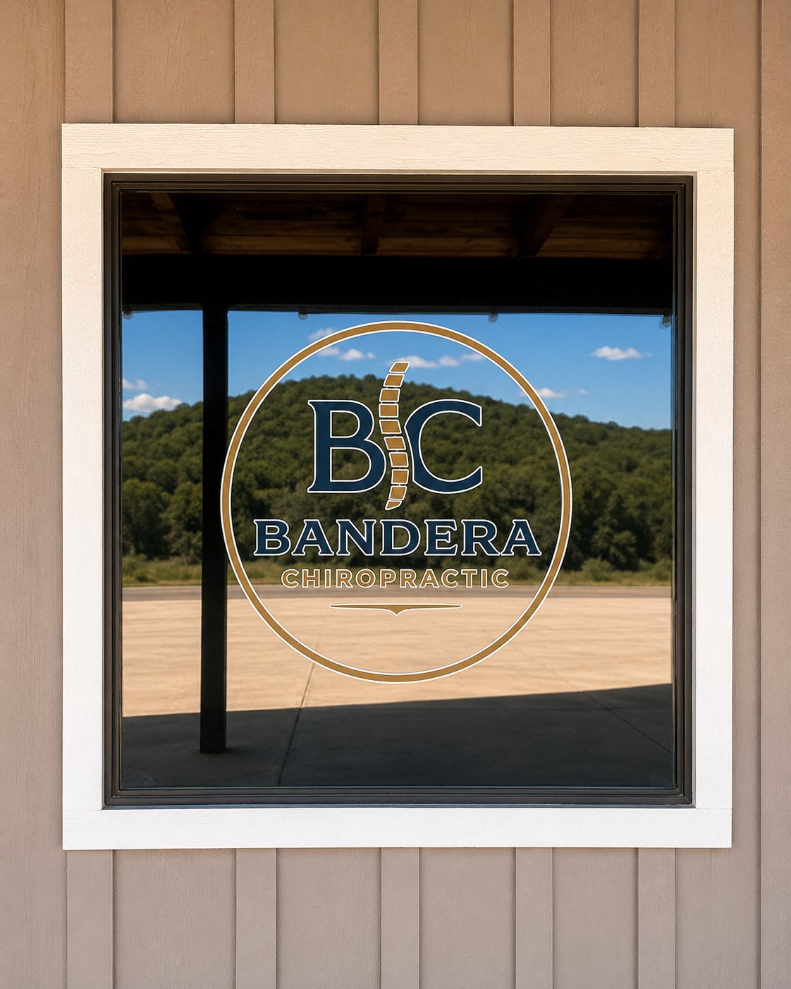 The Bandera Chiropractic logo on the office window, with the Hill Country reflected in the glass