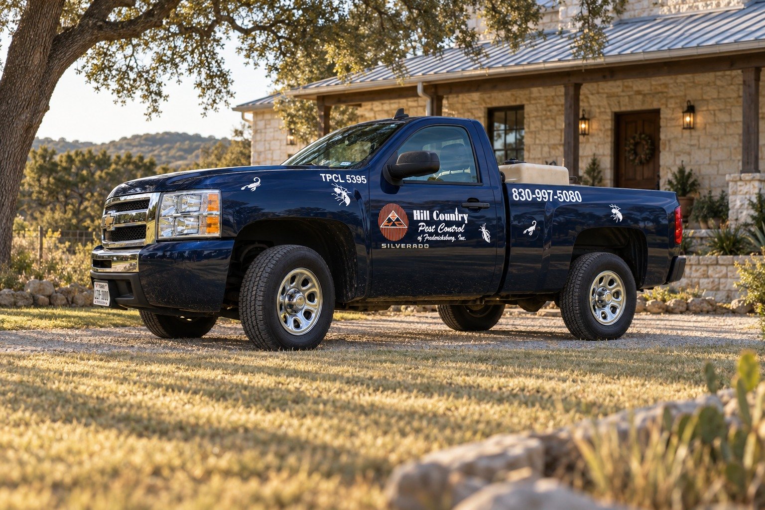 A Hill Country Pest Control of Fredericksburg truck parked in the drive of a limestone Hill Country home, late afternoon