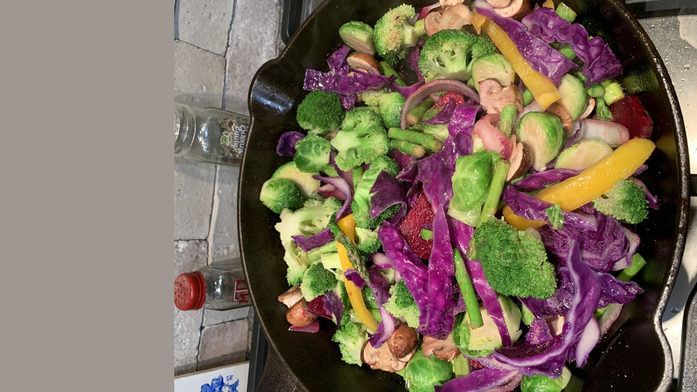 A vibrant cast-iron skillet of red cabbage, broccoli, and fresh vegetables